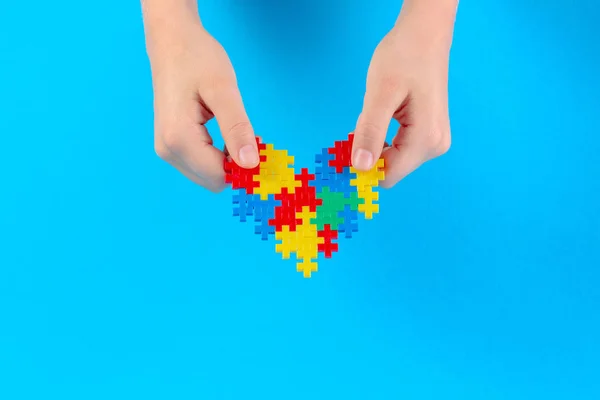 Kinderhand mit buntem Herz auf blauem Hintergrund. Konzept zum Welt-Autismus-Tag — Stockfoto