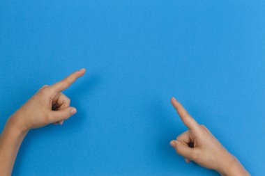 Mavi arka plan üzerinde bir şey işaret eden çocuk eller