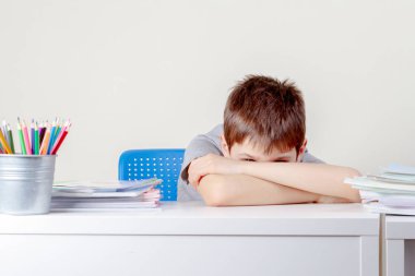 Okul kitapları ve defterler yığını ile üzgün okul çocuğu Üzgün