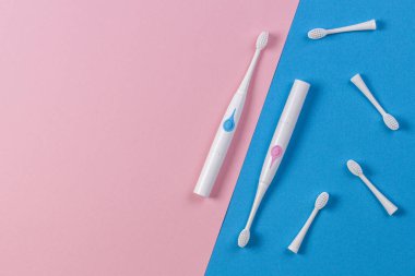 Mavi ve pembe arka planda fırça kafalı iki elektrikli diş fırçası. Üstte görüntü