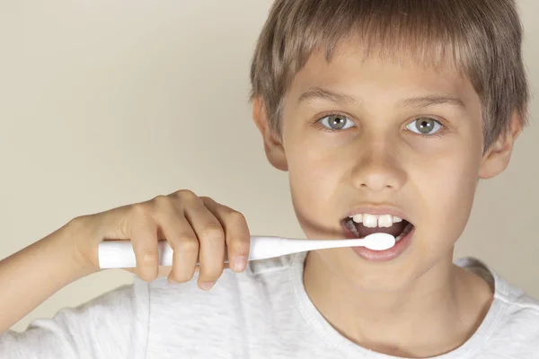 Kind putzt Zähne mit weißer elektrischer Zahnbürste — Stockfoto
