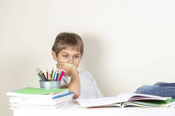 Triste criança cansada fazendo lição de casa na mesa e pensando — Fotografia de Stock