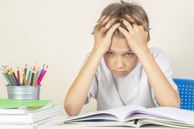 Yorgun okul kitapları ve defterler yığını ile üzgün okul çocuğu