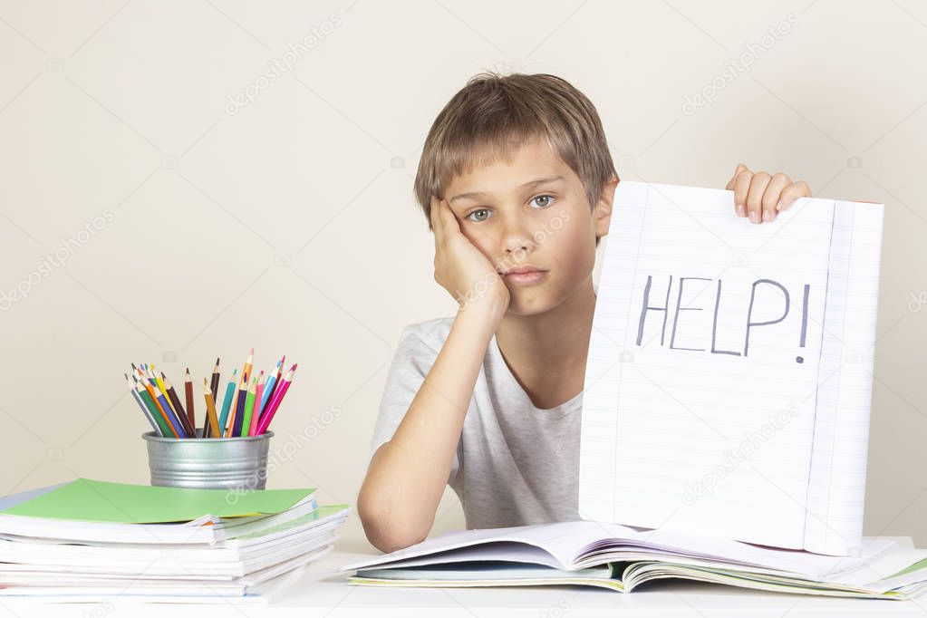 Help sign. Sad tired unhappy child doing homework and holding notebook with word Help