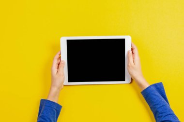 Tablet bilgisayarda sarı arka plan ile çocuk el