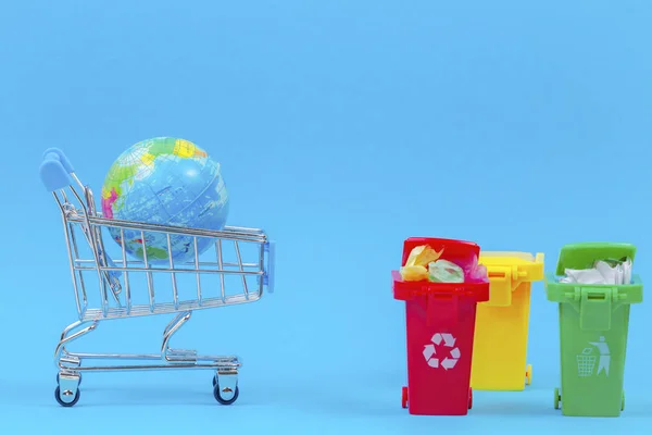 Ecología problema de contaminación ambiental planeta, consumismo, concepto de reciclaje. Coloridos contenedores de contenedores de reciclaje y carrito de compras con globo sobre fondo azul — Foto de Stock