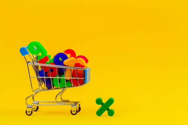 Panier ou chariot de supermarché plein de numéros colorés sur fond jaune — Photo