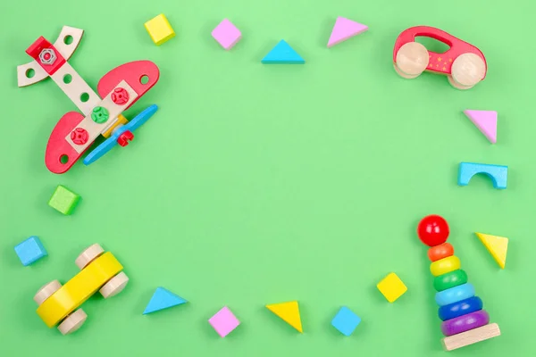 Kinderspielzeug Hintergrundrahmen mit Holzflugzeug, Autos, Baby Stapelringe Pyramide und bunte Blöcke auf grünem Hintergrund — Stockfoto