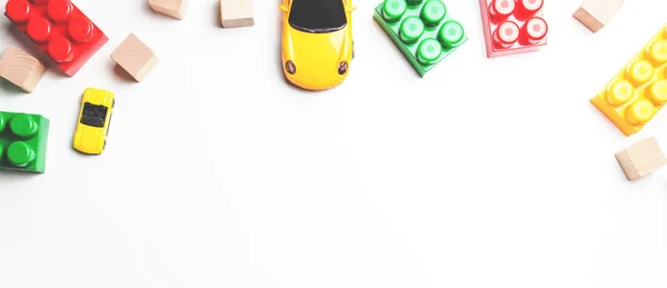 Marco de juguetes para niños con coches de juguete, ladrillos de plástico y bloques de madera sobre fondo blanco — Foto de Stock
