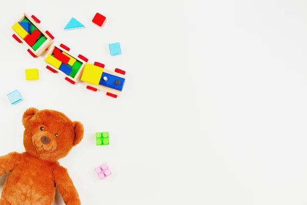 Bebê crianças brinquedos fundo. Urso de pelúcia, trem de madeira, tijolos coloridos na mesa branca — Fotografia de Stock