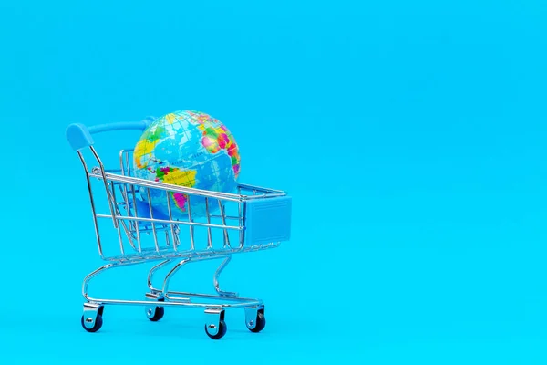 Mini Winkelwagen trolley met met Globe op blauwe achtergrond — Stockfoto