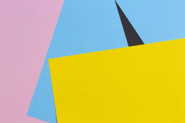 Forma geométrica abstracta amarillo, azul claro, rosa pastel y fondo de papel de color negro — Foto de Stock