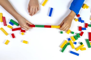 Eller iskambil ile plastik tuğla bina beyaz arka plan üzerinde renkli çocuklar. Eğitim gelişmekte olan oyuncaklar arka plan