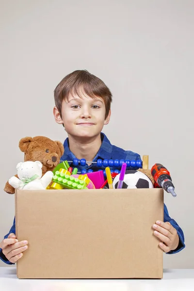 Conceito de doação. Kid holding doar caixa com roupas, livros e brinquedos — Fotografia de Stock