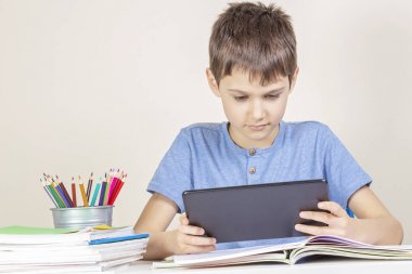 Çocuk Tablet bilgisayar ile masada kitap notebooklar oturuyor