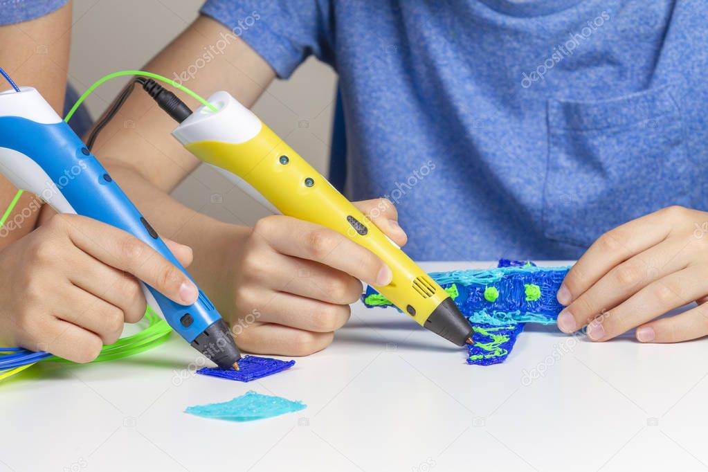 Two kid hands creating with 3d printing pens
