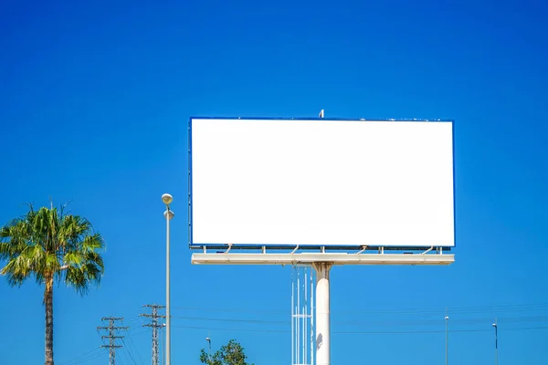 Burla de la cartelera en blanco grande, tablero de publicidad al aire libre en el fondo azul del cielo — Foto de Stock