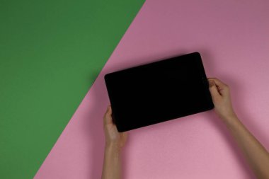 Pastel pembe ve açık yeşil arka plan üzerinde tablet bilgisayar ile Çocuk eller