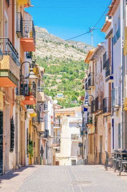 Finestrat, İspanya - 12 Haziran 2019: Finestrat eski şehrinde güzel evler ve dağ arka planı ile dar sokak