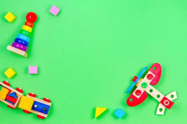 Bambino bambini giocattoli cornice di sfondo con treno in legno, aereo, bambino accatastamento anelli piramide e blocchi colorati su sfondo verde — Foto Stock