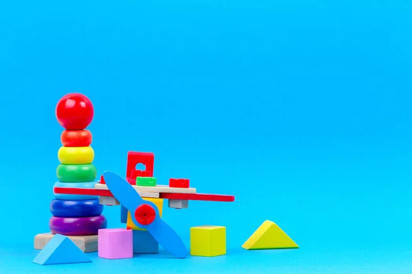 Baby kid toy background. Wooden toy plane, baby stacking rings pyramid and colorful blocks on blue background — Stock Photo, Image