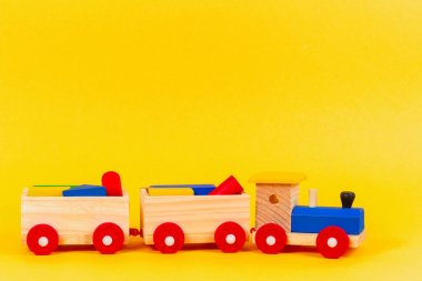 Ahşap oyuncak tren ile sarı arka plan üzerinde renkli blok