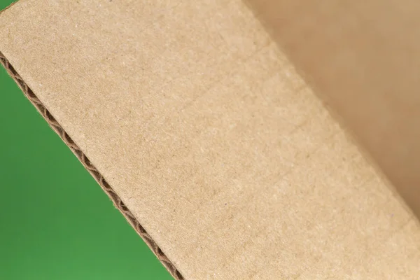 Крупним планом відкрита картонна коробка краю на зеленому фоні — стокове фото