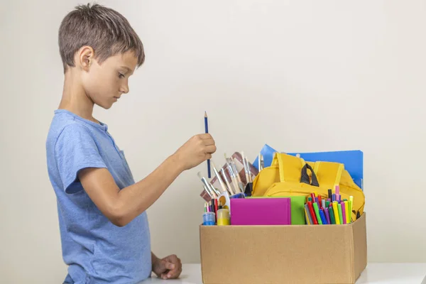 Concetto di donazione. Bambino che prepara donare scatola con libri, matite e materiale scolastico per la donazione — Foto Stock