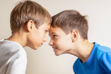 Two angry boys standing face to face, quarreling and looking at each other clipart