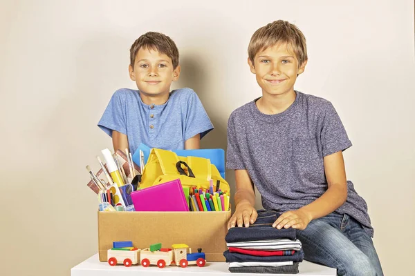 Concepto de donación. Niños sosteniendo caja de donaciones con libros y útiles escolares, ropa y juguetes —  Fotos de Stock