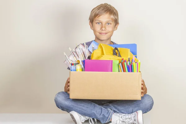 Donatie concept. Kid Holding doneren box met boeken, potloden en schoolbenodigdheden — Stockfoto