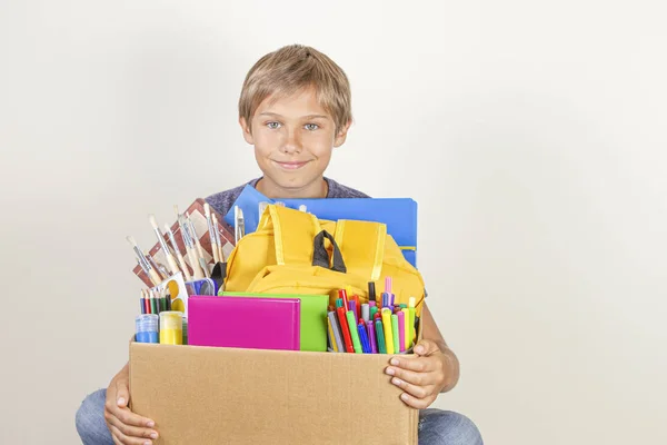 Adományozási koncepció. Kid Holding adományoz doboz könyvek, ceruzák és az iskolai kellékek — Stock Fotó