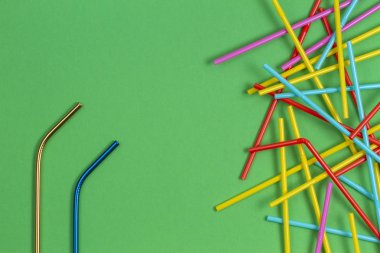 Açık yeşil arka planda çok renkli plastik pipetler ile paslanmaz çelik tekrar içme saman