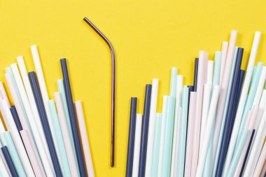 Sarı arka planda çok renkli plastik pipetler ile paslanmaz çelik tekrar içme saman