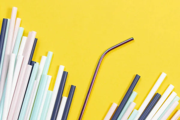Stainless steel reusable drinking straw with many multicolored plastic straws on yellow background — Stock Photo, Image