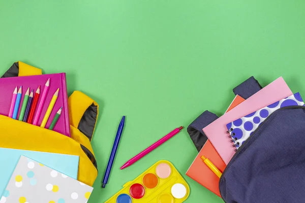 학교 개념으로 돌아갑니다. 노란색과 파란색 배낭 학교 용품, 책과 밝은 녹색 배경에 노트북. 맨 위 보기 — 스톡 사진
