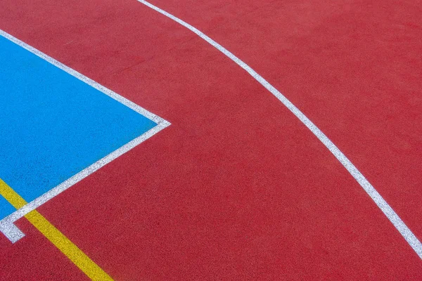 Colorful sports court background. Top view to red and blue field rubber ground with white and yellow lines outdoors