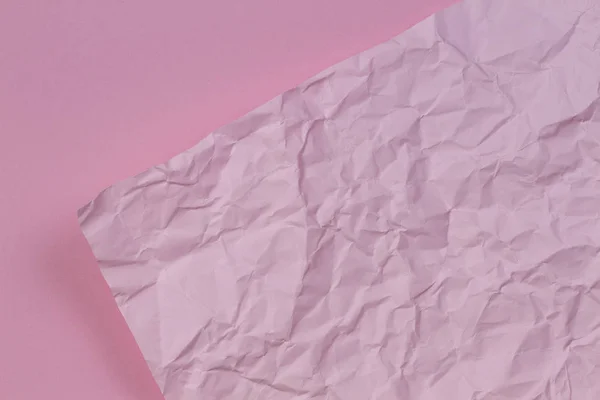 Pink crumpled wrinkled paper over blank pink paper texture background