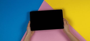 Tablet bilgisayarda mavi pembe ve sarı arka plan ile çocuk el