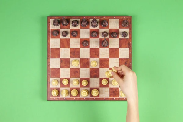 Kid hands over a chessboard playing chess game on green background, top view — Stock Photo, Image