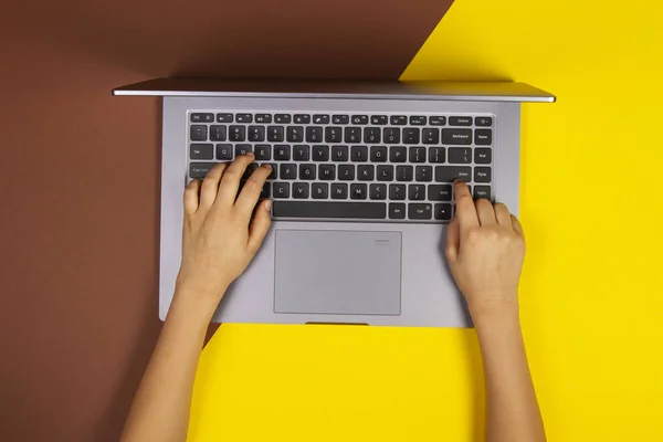 Dizüstü bilgisayar klavyesi, üst görünüm, sarı ve kahverengi arka plan üzerinde yazma çocuk elleri — Stok fotoğraf