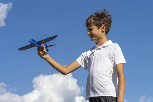 Chico jugando con azul juguete avión contra azul cielo — Foto de Stock