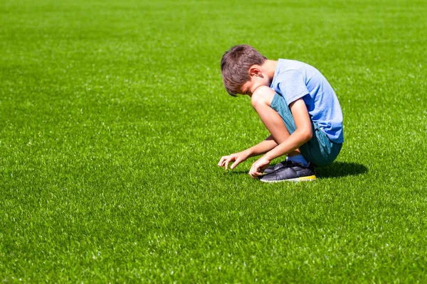Trauriger einsamer Junge, der im Gras sitzt — Stockfoto