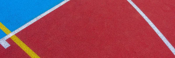 Colorful sports court background. Top view to red and blue field rubber ground with white and yellow lines outdoors