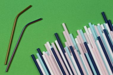 Yeşil arka plan üzerinde birçok çok renkli plastik pipetler ile iki paslanmaz çelik yeniden içme pipetleri. Üstte görüntü