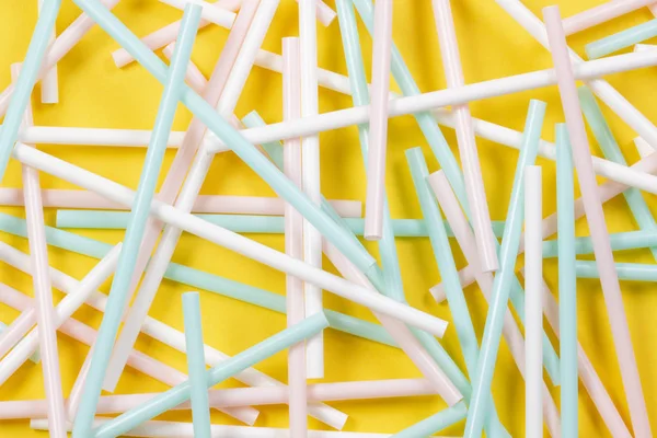 Multicolored plastic cocktail tubes straws on yellow background — Stock Photo, Image