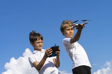 Çocuklar mavi gökyüzüne karşı yaz günü açık havada drone ile oynuyor