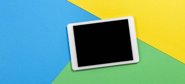 Açık mavi, yeşil ve sarı arkaplanda dijital tablet bilgisayar. Üst görünüm