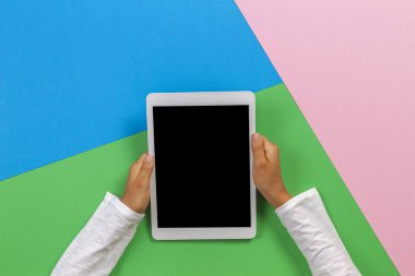 Pastel pembe, mavi ve yeşil arka plan üzerinde tablet bilgisayar ile Çocuk eller