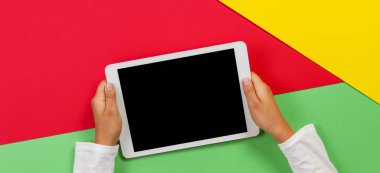Kırmızı, sarı ve yeşil arka planda tablet bilgisayar ile Çocuk eller